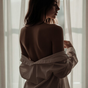 Fotografía boudoir de mujer de espalda desnuda contraluz de ventana